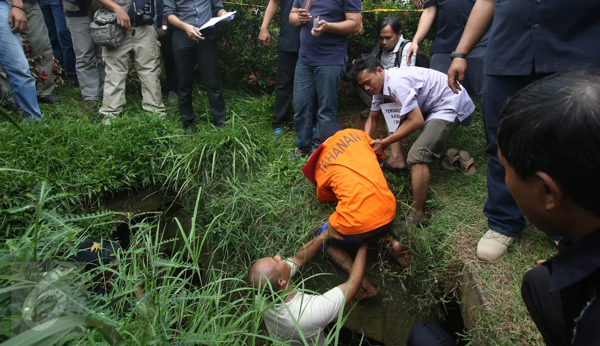 Seorang tersangka dibantu petugas pada rekonstruksi pencurian kabel gorong-gorong di Jalan Medan Merdeka Selatan, Jakarta, Selasa (15/3). Tersangka memperagakan cara masuk ke lubang gorong-gorong dan cara mencuri kabel. (Liputan6.com/Immanuel Antonius)