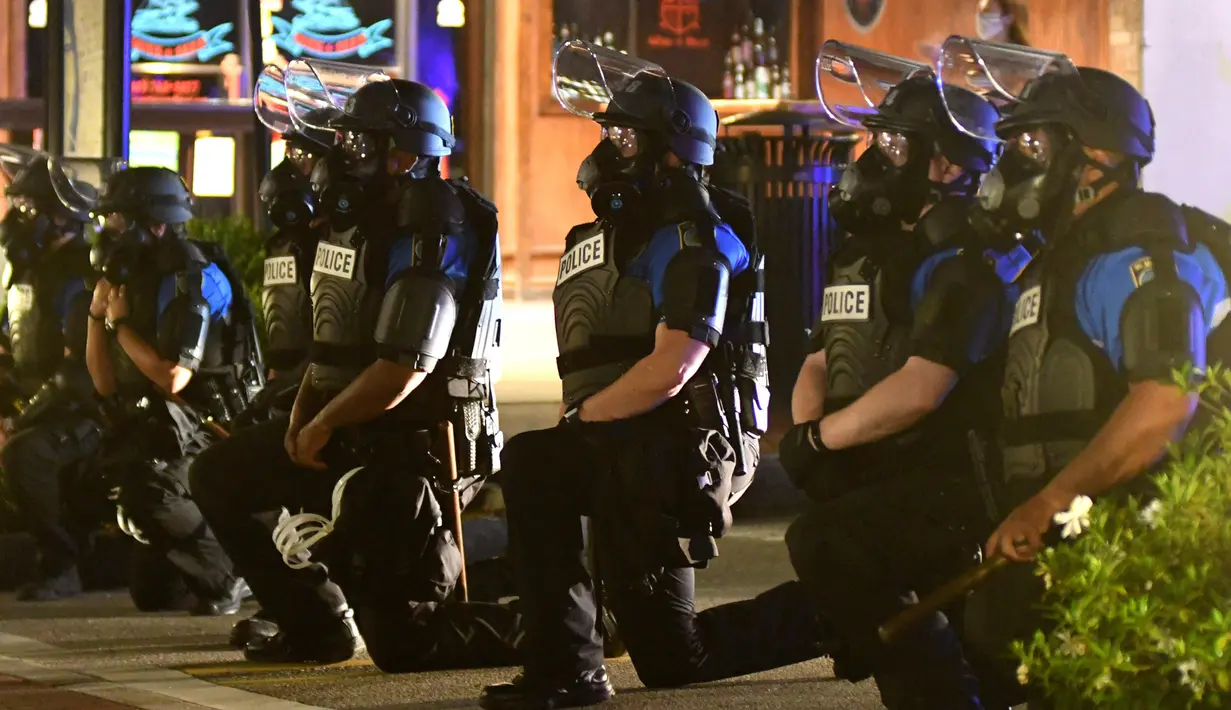 Petugas dan Departemen Kepolisian Wilmington berlutut setelah demonstran meneriakkan "Ambil lutut untuk George" di pusat kota Wilmington, North Carolina, 31 Mei 2020. George Floyd tewas tak bisa bernafas karena tercekik lutut polisi saat ditangkap pada (25/5) lalu. (Matt Born/The Star-News via AP)