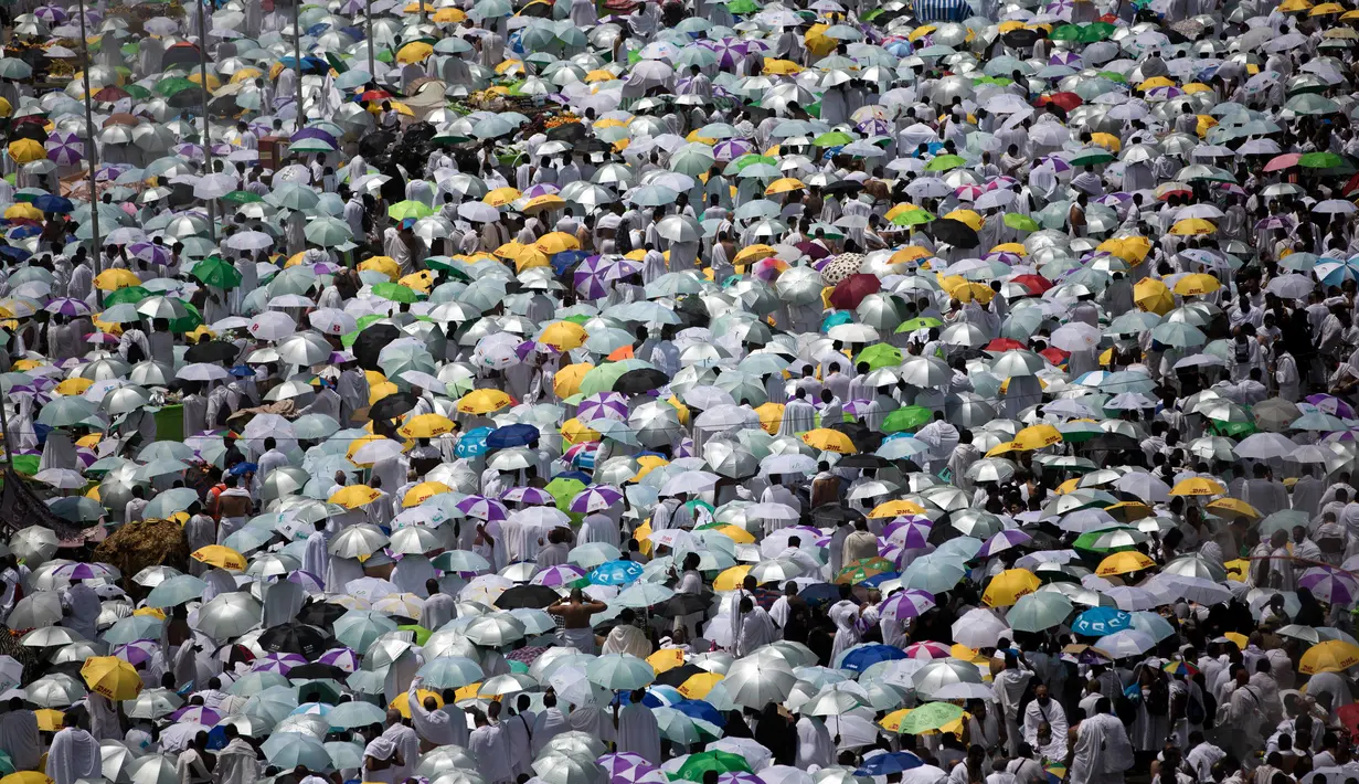 Jemaah membawa payung saat memadati masjid Namirah di Kota Arafah, Arab Saudi (31/8). Menurut hikayat setempat, masjid ini merupakan salah satu saksi pertama kali Rasulullah melaksanakan ibadah haji. (AP Photo / Khalil Hamra)