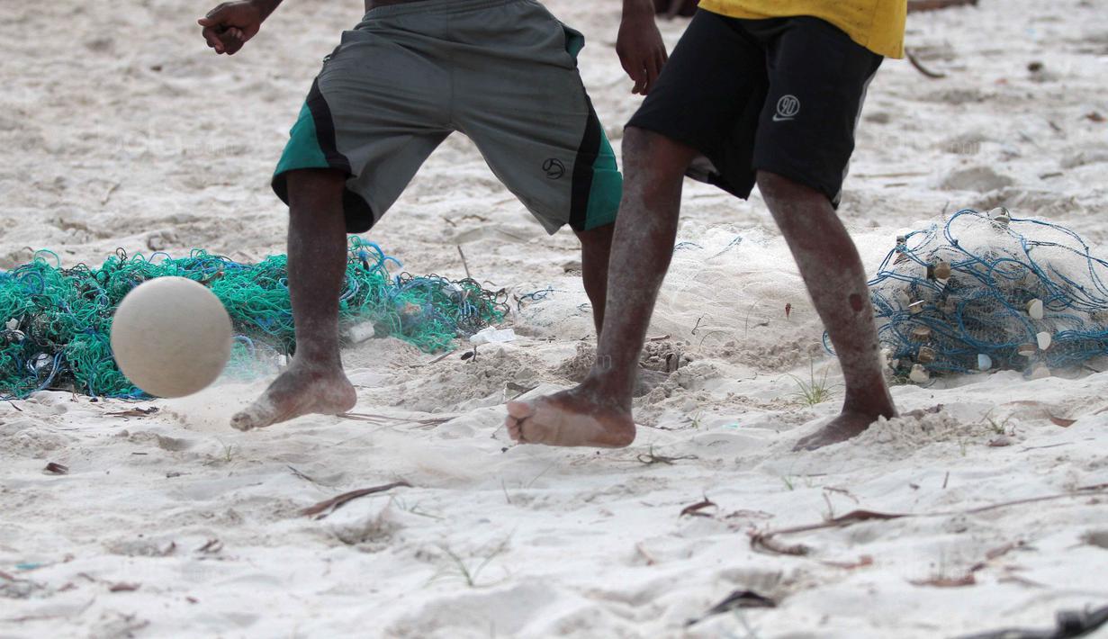 Kaki-kaki pemuda pemuda desa berebut bola saat bermain bola dekat pantai di Desa Matwaer, Kei Kecil, Maluku (25/12/2017).  Bermain bola di pasir menjadi daya tarik tersendiri bagi anak-anak dan pemuda desa. (Bola.com/Nick Hanoatubun)