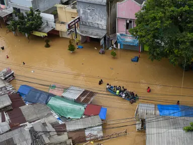 Warga mengungsi menggunakan perahu di kota Dayeuhkolot yang terendam banjir di Bandung pada 12 Januari 2024. (TIMUR MATAHARI/AFP)