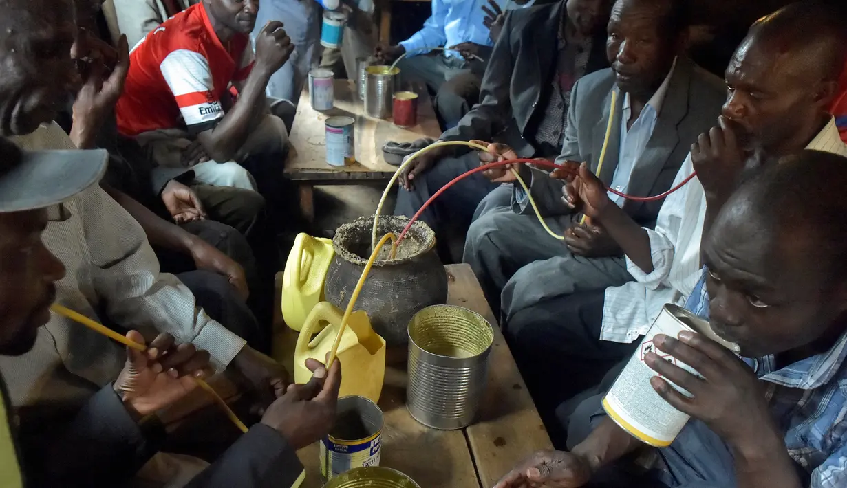 Sejumlah pria menggunakan selang kecil meminum air beralkohol dari pot yang disebut Busaa di daerah Nairobi, Kenya, Rabu (8/11). (AFP Photo/Simon Maina)