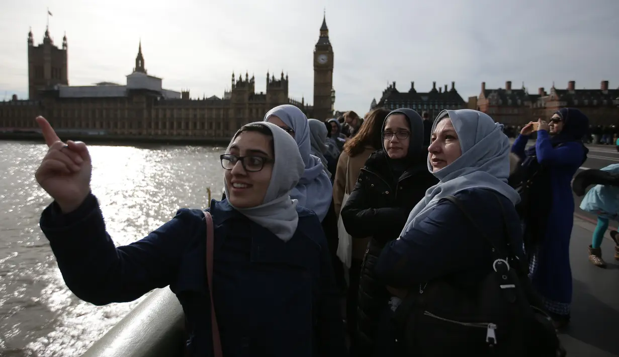 Para perempuan dari beragam etnis mengenakan warna biru berkumpul di Jembatan Westminster, London, Minggu (26/3). Mereka melakukan aksi solidaritas mengenang korban teror London dengan saling bergandengan tangan selama lima menit. (Daniel LEAL-OLIVAS/AFP)