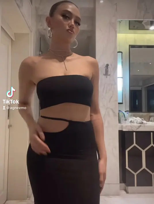 Kembali tampil seksi, Agnez Mo mengenakan atasan kemben dan skirt panjang cut out warna hitam. Dengan aksesori kalung dan anting-antingnya. (@agnezmo)