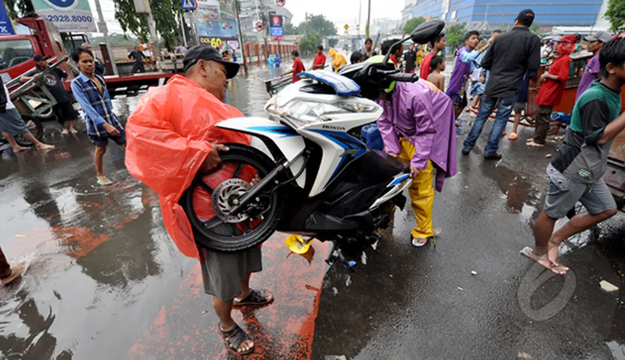 Pengendara motor berusaha menghidupkan motornya yang mati akibat menerjang banjir, Jakarta, Senin (6/2/2015).  Hujan yang turun sejak malam hingga kini membuat sejumlah ruas jalan tergenang air. (Liputan6.com/Faizal Fanani)