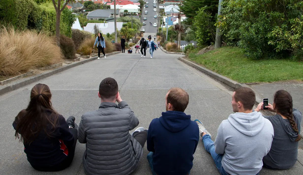 Wisatawan duduk di tengah jalanan paling curam di dunia, Baldwin Street, di kota Dunedin, Selandia Baru, 26 Agustus 2017. Jalan ini terletak di suburb North East Valley, 3,5 kilometer timur laut dari pusat kota Dunedin. (AP Photo/Mark Baker)