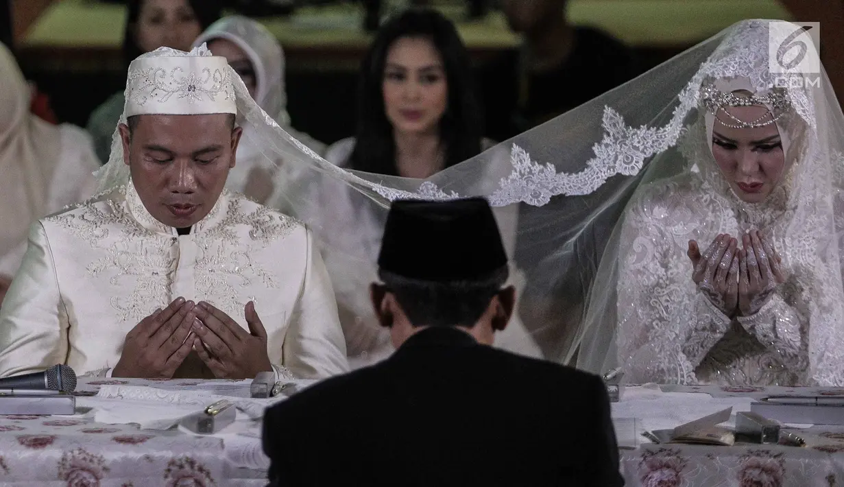 Vicky Prasetyo dan Angel Lelga membaca doa saat menggelar akad nikah di Mesjid Istiqlal, Jakarta, Jumat (9/2). Pasangan pengantin memilih gaun berwarna putih. (Liputan6.com/Faizal Fanani)