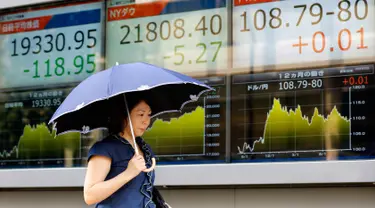 Seorang wanita berjalan melewati sebuah indikator saham elektronik sebuah perusahaan sekuritas di Tokyo (29/8). Akibat peluncuran rudal Korea Utara yang mendarat di perairan Pasifik saham Asia menglami penurunan. (AP Photo/Shizuo Kambayashi)