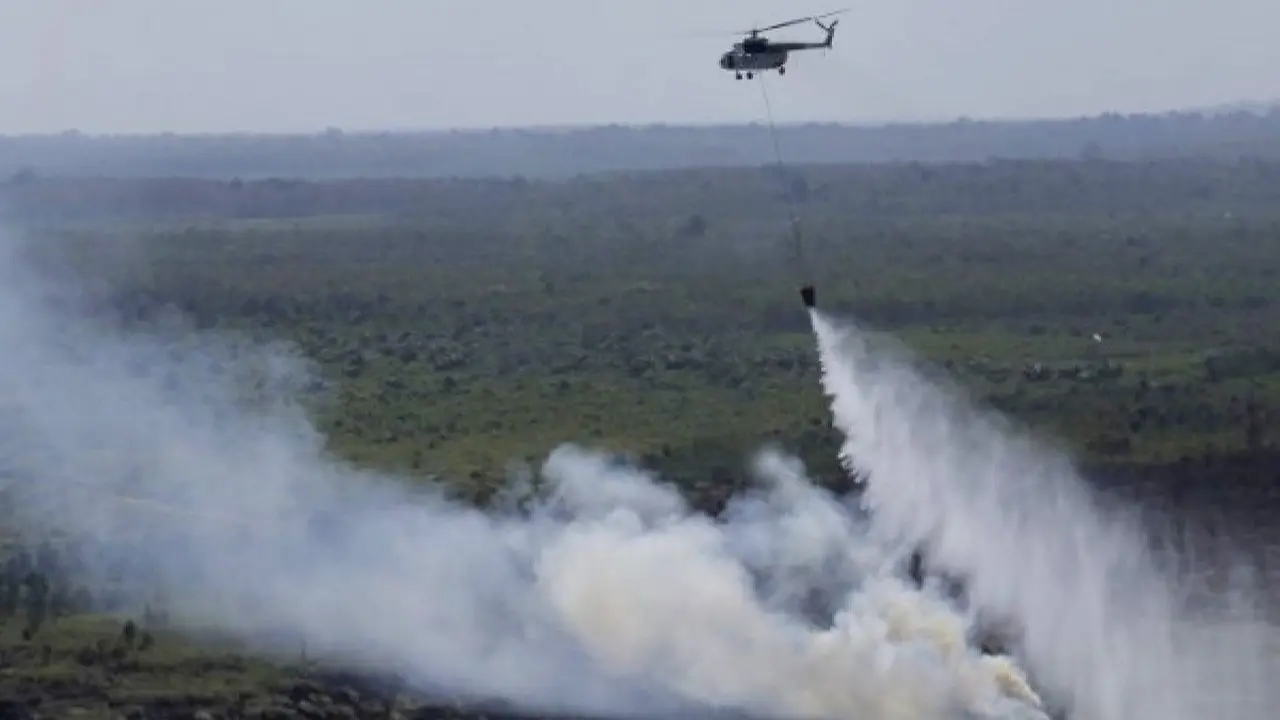 Helikopter melakukan water bombing di lahan yang terbakar.