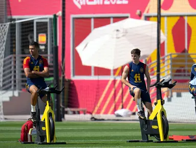 Pemain Spanyol Rodri (kiri) dan Gavi (tengah) berlatih sepeda statis di samping pelatih Lorenzo del Pozo selama sesi latihan di Universitas Qatar, Doha, Qatar, Selasa (29/11/2022). Spanyol akan melawan Jepang dalam pertandingan Grup E Piala Dunia 2022 pada 1 Desember mendatang. (AP Photo/Julio Cortez)