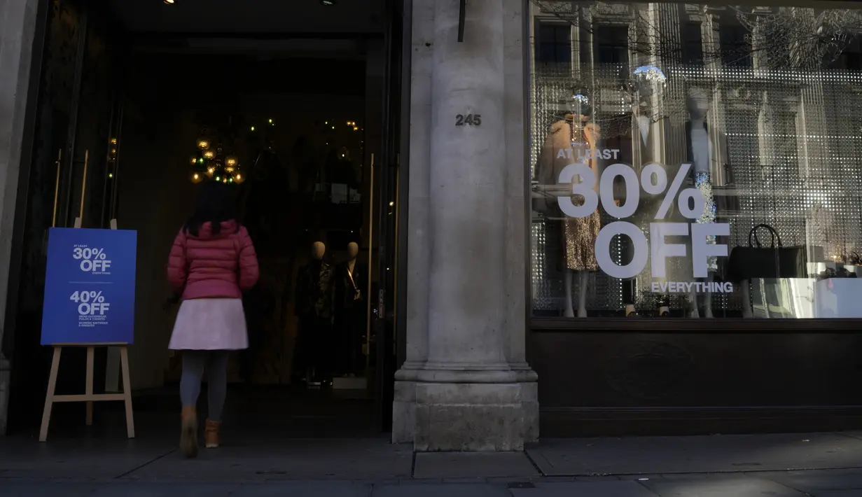 Seorang perempuan muda memasuki toko yang mengiklankan obral di Regent Street di London, Rabu (16/11/2022).  Inflasi Inggris menembus 11,1 persen pada bulan Oktober 2022 dan mencapai rekor tertinggi sepanjang 41 tahun. (AP Photo/Alastair Grant)