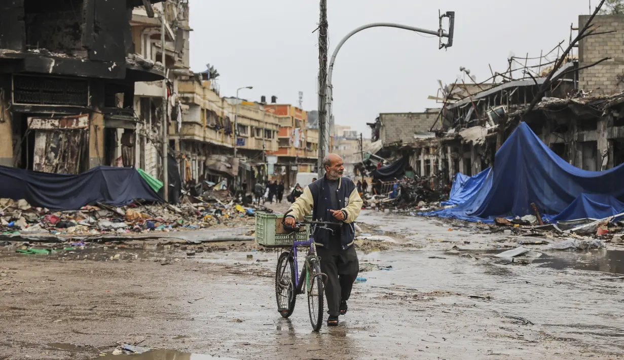 Seorang warga Palestina berjalan di Kota Gaza pada hari keempat gencatan senjata sementara antara Hamas dan Israel, Senin (27/11/2023). (AP Photo/Mohammed Hajjar)
