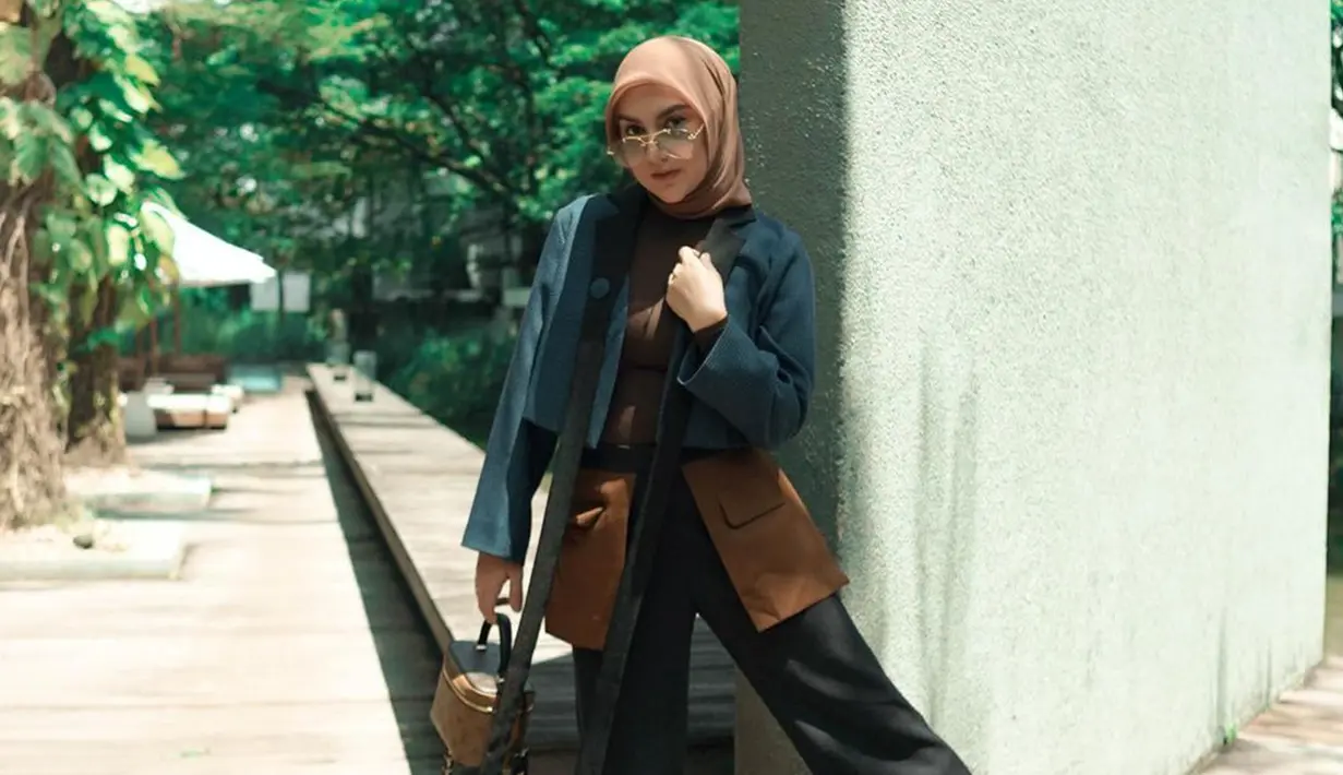 Gaya penampilan Irish Bella Menggunakan busana kombinasi warna cokelat, navy dan hitam ini juga tak lepas dari sorotan. Bahkan, ia terlihat memilih memadukan penampilannya dengan hijab serta tas dengan warna senada. (Liputan6.com/IG/@_irishbella_)