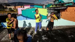 Anak-anak bermain di sekitar kawasan kumuh El Pesebre, pinggiran Medellin, Kolombia, 19 Juni 2017. Seniman Prancis, Tarik Bouanani melukis 230 rumah di kawasan tersebut sebagai bagian dari proyek seninya membentuk mural raksasa. (JOAQUIN SARMIENTO/AFP)