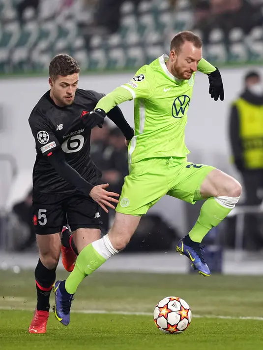 Pemain Lille Gabriel Gudmundsson (kiri) berebut bola dengan pemain Wolfsburg Maximilian Arnold pada pertandingan sepak bola Grup G Liga Champions di Wolfsburg, Jerman, 8 Desember 2021. Lille menang 3-1. (AP Photo/Martin Meissner)