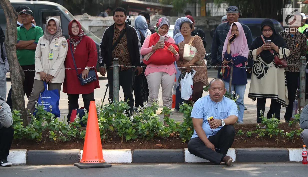 Sejumlah warga berdiri di sisi jalan TMP Kalibata untuk melihat prosesi pemakaman Presiden RI ke-3 BJ Habibie, Jakarta, Kamis (12/9/2019). BJ Habibie meninggal dunia pada Rabu (11/9/2019) pukul 18.05 WIB di usia 83 tahun. (Liputan6.com/Helmi Fithriansyah)