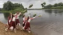 Wanita Belarusia yang mengenakan kostum nasional melemparkan karangan bunga ke Sungai Berezina pada Hari Ivan Kupala di Desa Parichi, sekitar 200 km (125 mil) selatan Parichi, Belarus, 6 Juli 2022. Hari Ivan Kupala merupakan sebuah perayaan malam kuno yang menandai Titik Balik Matahari Musim Panas, malam terpendek tahun ini. (AP Photo/Viktor Drachev)