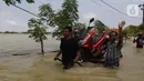 Warga membawa motor saat banjir di Desa Sukalaksana Kabupaten Bekasi, Jawa Barat, Senin (22/02/2021). Hujan dengan intensitas tinggi turun sejak Jumat, 19 Februari 2021 mengakibatkan air di aliran sungai meluap. (Liputan6.com/Herman Zakharia)
