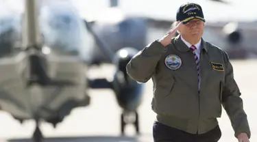 Presiden AS, Donald Trump memberi hormat saat berjalan menuju pesawat Air Force One sebelum berangkat dari Pangkalan Udara Langley di Virginia, (2/3). Trump tampak gagah mengenakan jaket panglima tertinggi Navy Seal. (AFP Photo / Saul Loeb)