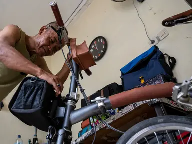 Taylor Amin Robert melakukan test-fit sebuah tas sepeda buatan tangannya di rumahnya, Jakarta (18/2/2020). Taylor yang otodidak memulai karirnya 30 tahun lalu, sekarang berspesialisasi dalam tas sepeda, dengan mayoritas klien mengendarai sepeda lipat di jalan-jalan kota. (AFP/Bay Ismoyo)