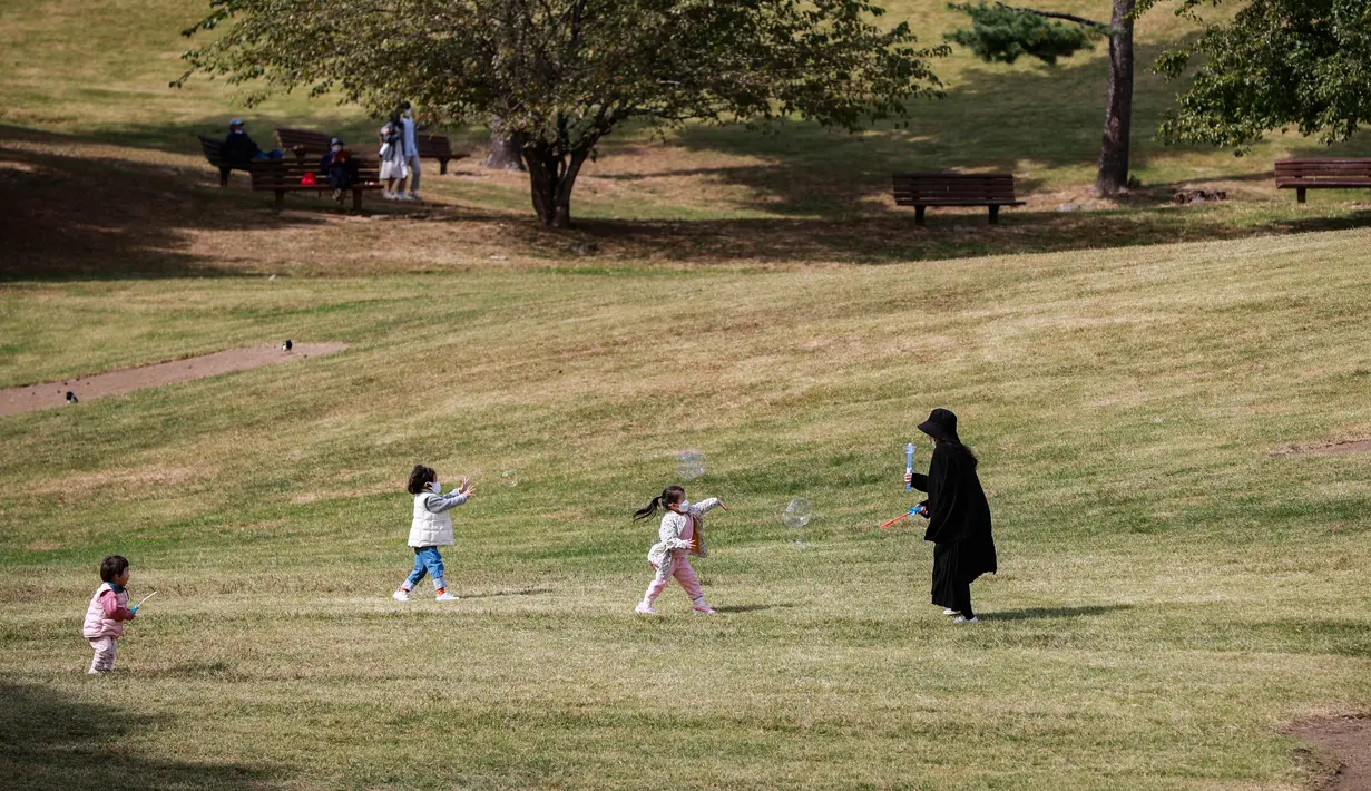 Anak-anak mengejar gelembung yang ditiupkan seorang wanita di Taman Olimpiade di Seoul, Korea Selatan (15/10/2020). Banyak warga memilih datang ke taman-taman publik untuk melakukan aktivitas luar ruangan di tengah musim gugur. (Xinhua/Wang Jingqiang)