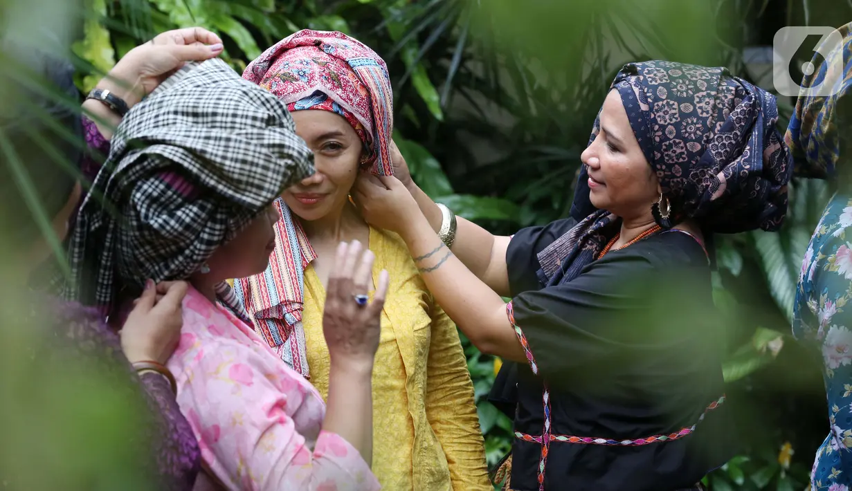 Perempuan belajar mengenakan penutup kepala Tengkuluk pada acara Ngopi Tengkuluk, Mengenal Penutup Kepala Perempuan Indonesia di Depok, Minggu (26/09/2021). Tengkuluk biasa disebut takuluk atau kuluk berkembang di lingkungan suku Melayu di Kota Jambi dan Pantai Timur Sumatra.(Liputan6.com/HO/Sybli)