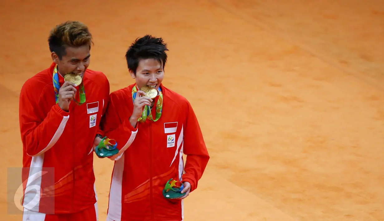 Pasangan ganda campuran Indonesia, Tontowi Ahmad dan Liliyana Natsir mengigit medali emas usai mengalahkan lawannya asal Malaysia Peng Soon Chan dan Liu Ying Goh pada final bulutangkis di Riocentro Pavilion 4 , Brasil. (REUTERS/Mike Blake)
