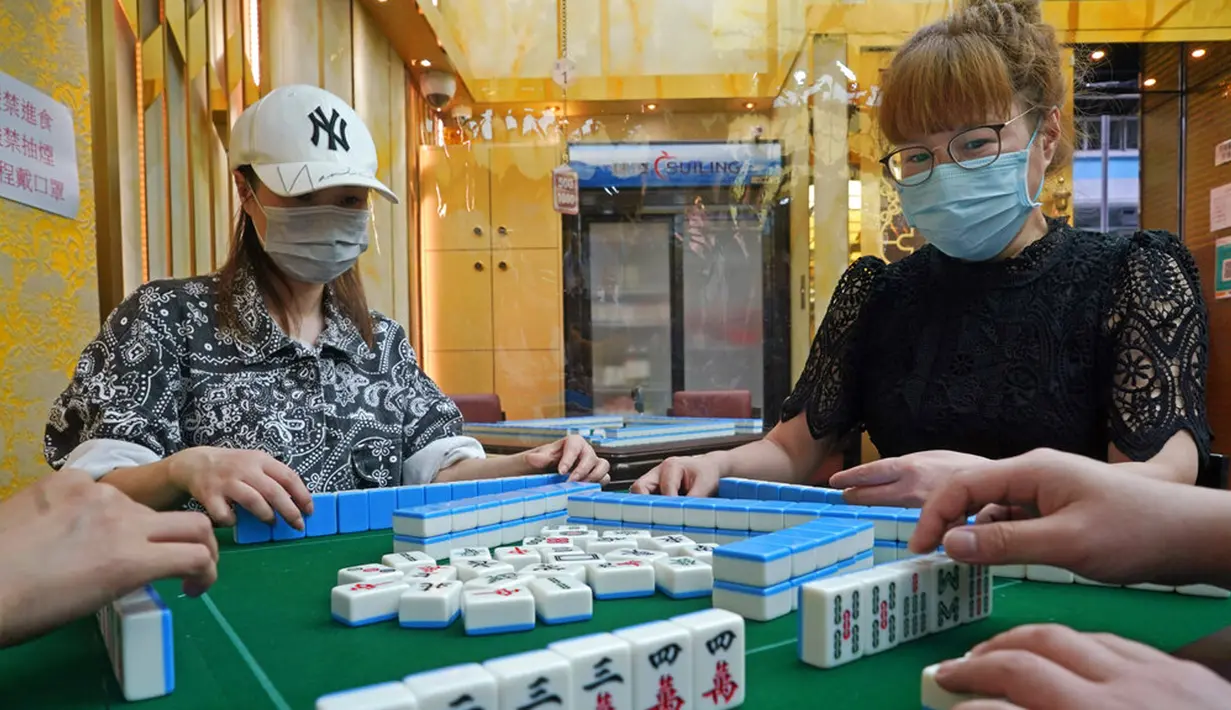 Staf yang mengenakan masker memperagakan langkah-langkah keamanan kepada media di ruang tamu mahjong di Hong Kong, Rabu (28/4/2021). Pejabat kesehatan Hong Kong mengumumkan bahwa mereka akan melonggarkan langkah-langkah terkait COVID-19 mulai 29 April 2021. (AP Photo/Kin Cheung)