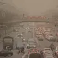 Mobil dan pejalan kaki menyusuri jalan yang diselimuti debu dan kabut di Beijing, Jumat, 10 Maret 2023. Pencakar langit menghilang ke dalam kabut dan kualitas udara anjlok saat ibu kota China diselimuti badai debu dan polusi berat. (AP Photo/Mark Schiefelbein)