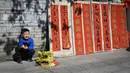 Seorang anak berpose untuk difoto di samping kuplet musim semi, semacam dekorasi Tahun Baru Imlek, jelang dimulainya Tahun Baru Imlek di sebuah kios di Foshan, Provinsi Guangdong, China, 18 Januari. Ada banyak versi dan gaya yang berbeda, tetapi setiap bait dalam kuplet menyampaikan keinginan penulis untuk tahun baru. (Giok Gao/AFP)