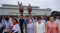 Warga Pyongyang berjalan di depan patung pemimpin Korea Utara Kim Il Sung (kiri) dan Kim Jong Il (kanan), setelah meletakkan bunga untuk menandai peringatan 24 tahun kematian Kim Il Sung, di bukit Mansu, Minggu (8/7). (AFP/KIM Won-Jin)