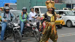 Seniman berpakaian seperti "Yamaraj" (R), dewa kematian Hindu mengatur lalu lintas di Bangalore (10/7). Kampanye ini bertujuan untuk membawa kesadaran pengendara tentang pentingnya peraturan keselamatan lalu lintas. (AFP Photo/Manjunath Kiran)