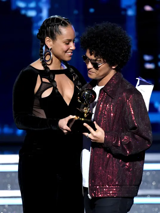 Penyanyi Bruno Mars menerima trofi Record of the Year dari Alicia Keys pada ajang Grammy Awards 2018 di New York City, Minggu (28/1). Dengan album 24K Magic, Bruno merebut enam trofi Grammy termasuk Record of the Year. (Kevin Winter/Getty Images/AFP)