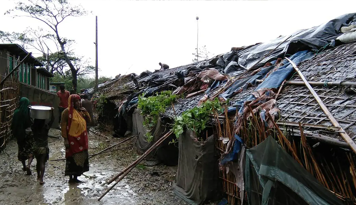 Pengungsi Rohingya berjalan di samping gubuk di sebuah kamp darurat di distrik Cox's Bazar di Bangladesh pada tanggal 30 Mei 2017 setelah Topan Mora mendarat di wilayah tersebut. (AFP Photo/Str)