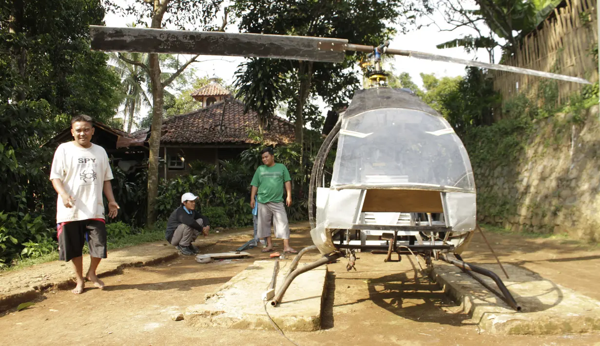 Gambar yang diambil pada 17 November 2019, Jujun Junaedi (kiri) menyelesaikan pembuatan helikopter buatannya di halaman belakang rumahnya di Sukabumi. Jujun yang berusia 41 tahun ini menargetkan helikopter berbahan bakar bensinnya rakitannya dapat diuji terbang pada akhir 2019. (Wulung WIDARBA/AFP)