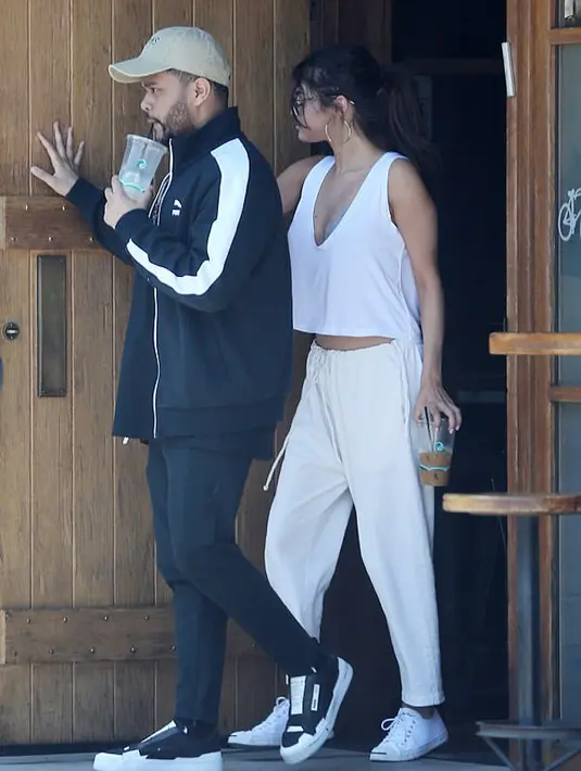 Gaya berpakaian keduanya sangat santai. Selena mengenakan outfit serba putih dengan atasan tanpa lengan,celana panjang, dan sneakers warna putih. The Weeknd memakai jaket olaah raga, celana, dan sepatu kets serbahitam. (doc. Daily Mail)