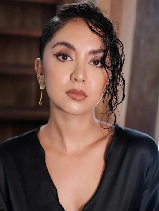 Rambut keriting Tasha ditata bergaya wet look dengan sanggul modern dan poni keriting menyamping [@weddingbynik]