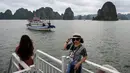 Wisatawan domestik berpose untuk foto di atas kapal di tengah Ha Long Bay, Quang Ninh, Vietnam, (16/5/2020). Seiring dengan meredanya virus corona, Ha Long Bay kawasan yang menjadi situs warisan dunia UNESCO kembali didatangi ratusan wisatawan. (AFP/Manan Vatsyayana)