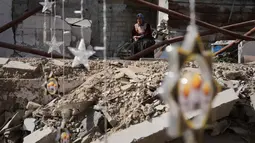 Beberapa pengungsi membuat lentera Ramadan dari kaleng bekas atau kain selimut bantuan. Tampak dalam foto, seorang wanita Palestina memperhatikan orang lain menggantung hiasan Ramadan di samping reruntuhan rumah yang hancur di Khan Younis, Jalur Gaza selatan, Minggu 15 Februari 2026. (AP Photo/Abdel Kareem Hana)