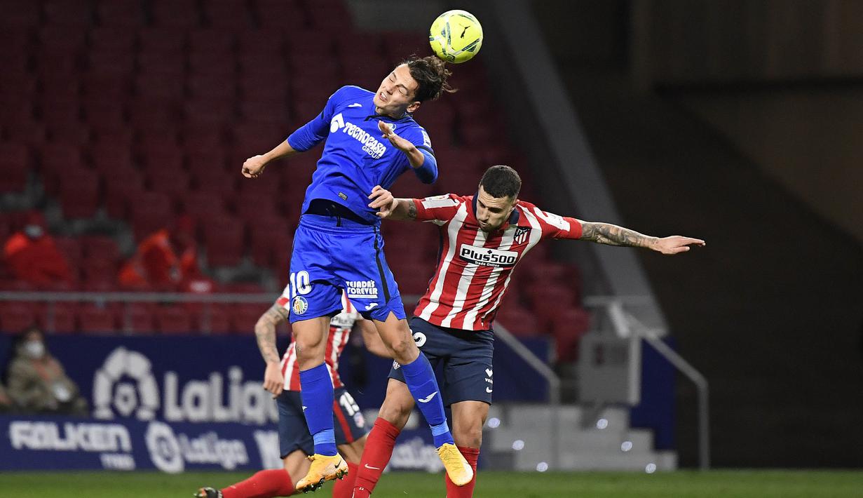 Bek Atletico Madrid, Mario Hermoso, duel udara dengan pemain Getafe, Enes Unal, pada laga Liga Spanyol di Stadion Wanda Metropolitano, Rabu (30/12/2020). Atletico Madrid menang dengan skor 1-0. (AFP/Oscar Del Pozo)