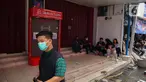Beberapa orang terlihat duduk di depan sejumlah toko dan perkantoran yang tutup di sekitar kompleks dengan Glodok Plaza, Jakarta, Kamis (16/1/2025). (Liputan6.com/Angga Yuniar)