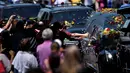 Beberapa orang berusaha menyentuh mobil jenazah Muhammad Ali menuju pemakaman Cave Hill di Louisville, Kentucky, AS, (10/6/2016). Ribuan orang memberi penghormatan terakhir di sepanjang jalan menuju pemakaman. (AFP/Brendan Smialowski)