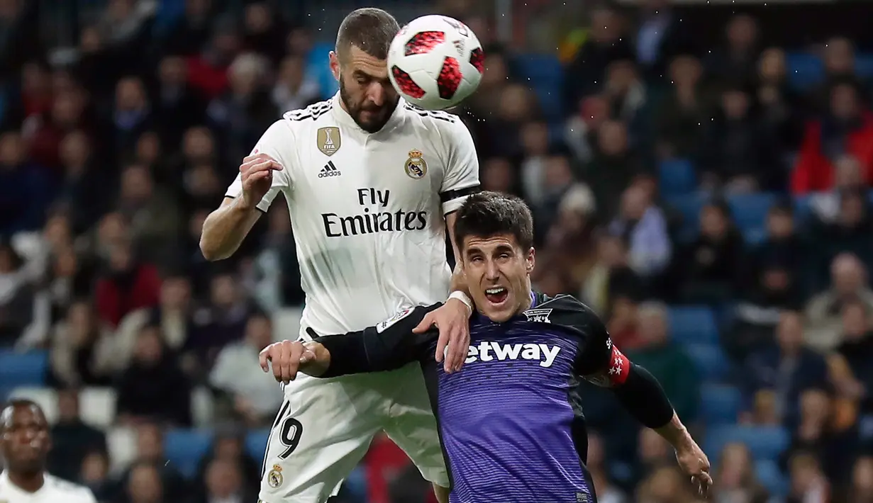 Pemain Real Madrid, Karim Benzema melakukan sundulan saat berebut bola dengan pemain Leganes, Unai Bustinza pada laga leg pertama babak 16 besar Copa del Rey di Santiago Bernabeu, Rabu (9/1). Madrid sukses mengandaskan Leganes 3-0. (AP/Manu Fernandez)