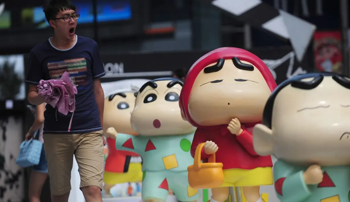 Seorang pria berjalan di dekat berbagai patung figure Crayon Shin-chan saat pameran Crayon Shin-chan di Shenyang, China, 11 Juli 2015. Pameran ini menandai ulang tahun ke 25 dari seri manga Jepang, Crayon Shin-chan. (CHINA OUT AFP PHOTO)