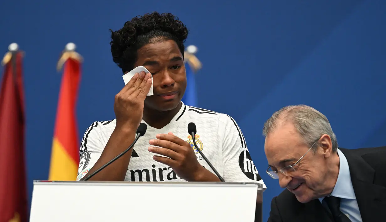 Pemain depan Brasil Endrick Felipe menyeka air matanya saat dia berdiri di samping presiden Real Madrid Florentino Perez selama penampilan pertamanya sebagai pemain baru Real Madrid di Stadion Santiago Bernabeu, Sabtu (27/7/2024). (JAVIER SORIANO / AFP)