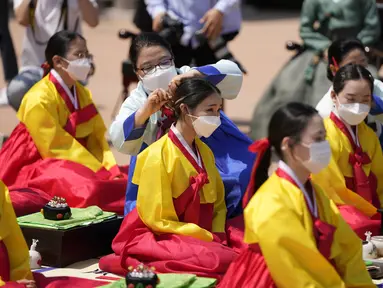 Wanita mengenakan pakaian tradisional Korea Selatan menghadiri upacara untuk menghidupkan kembali Hari Kedewasaan ke-50 di Desa Hanok Namsangol di Seoul, Korea Selatan (16/5/2022). Upacara diadakan untuk pria dan wanita muda yang akan berusia 20 tahun. (AP Photo/Lee Jin-man)