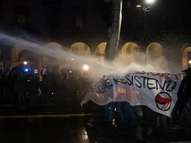 Aktivis antifasis melindungi diri mereka saat ditembakan meriam air oleh petugas keamanan setempat saat menggelar demonstrasi di Turin, Italia (22/2). (AFP Photo/Piero Cruciatti)