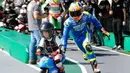 Pembalap MotoGP Alex Rins membantu seorang anak laki-laki mengendarai motor listrik mini saat acara jumpa pers jelang MotoGP Jepang di sirkuit Twin Ring Motegi, Jepang (12/10). (AP Photo / Shizuo Kambayashi)