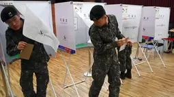 Tentara Korea Selatan (Korsel)  keluar dari bilik suara di sebuah TPS di Seoul, Kamis (4/5). Selama 2 hari, masyarakat yang terdaftar sebagai pemilih dapat memberikan suara sebelum pemilihan presiden (Pilpres) pada 9 Mei mendatang. (JUNG Yeon-Je/AFP)