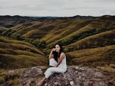 Wanita berdarah Indonesia-Swiss ini berpose dengan latar belakang Bukit Warinding Sumba yang sangat menakjubkan. Menggunakan pakaian serba putih, Anggika tampak santai tanpa menggunakan alas kaki. (Liputan6.com/IG/@anggikabolsterli)